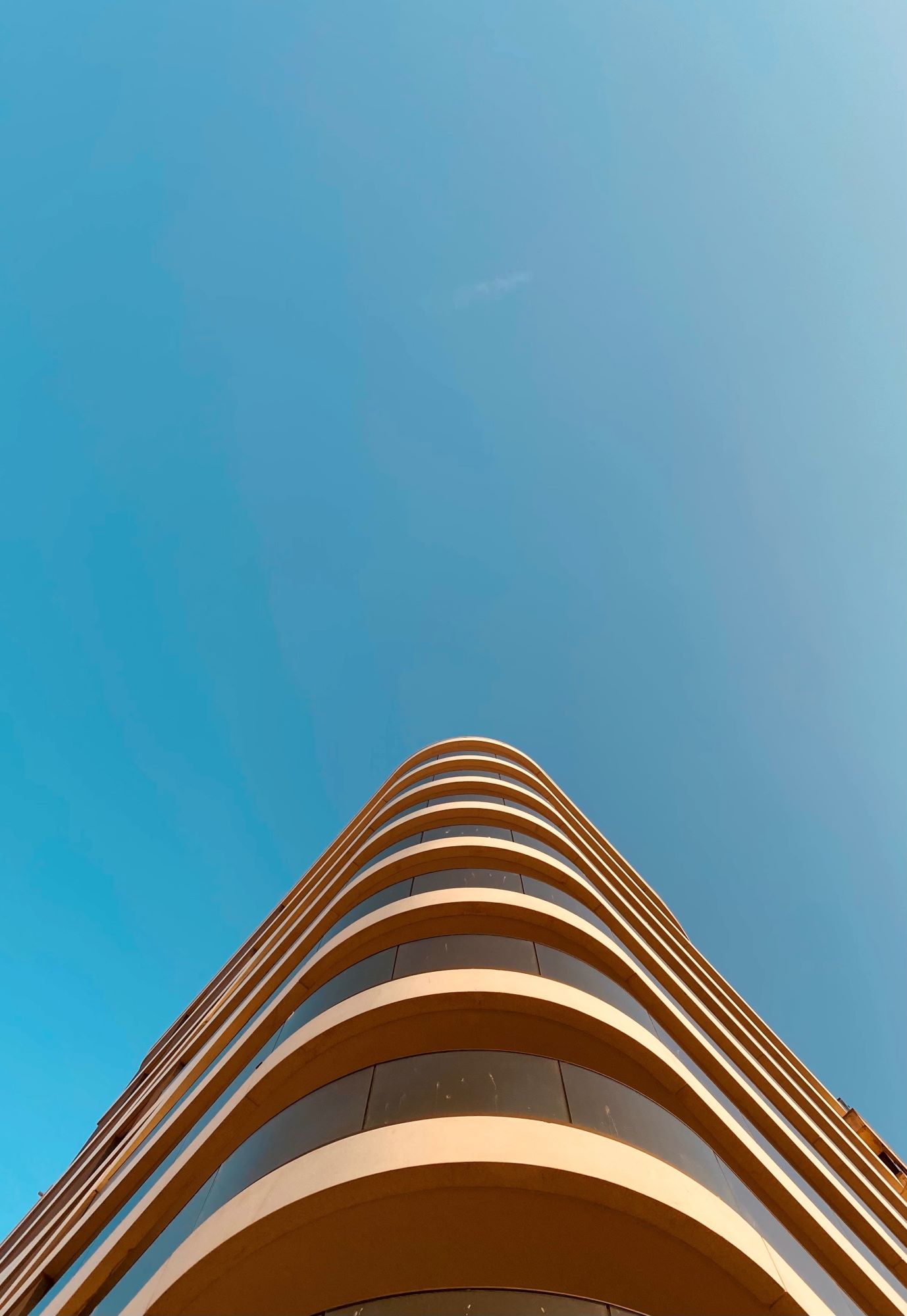Strahlend blauer Himmel und das angeschnittene Dach eines oval verlaufenden Hauses