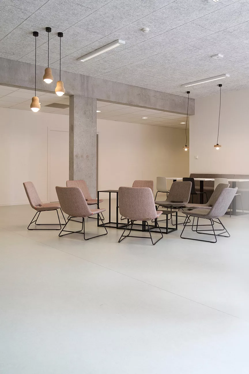 Offene Bürofläche mit warmen Natur-Farben, gemütlichen Sesseln und dekorativen Deckenleuchten