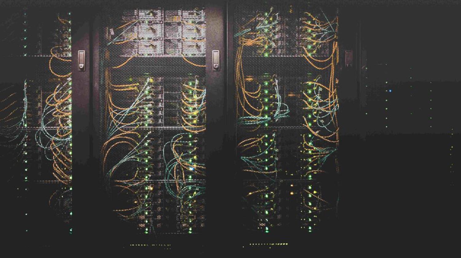 Blick auf schwarze verschlossene Serverschränke mit vielen bunten Kabeln