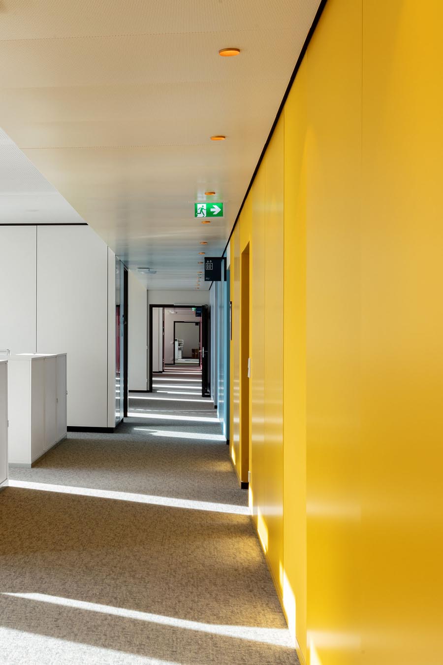 Langer Flur mit gelber Wand im Büro der DIN Zentrale Berlin