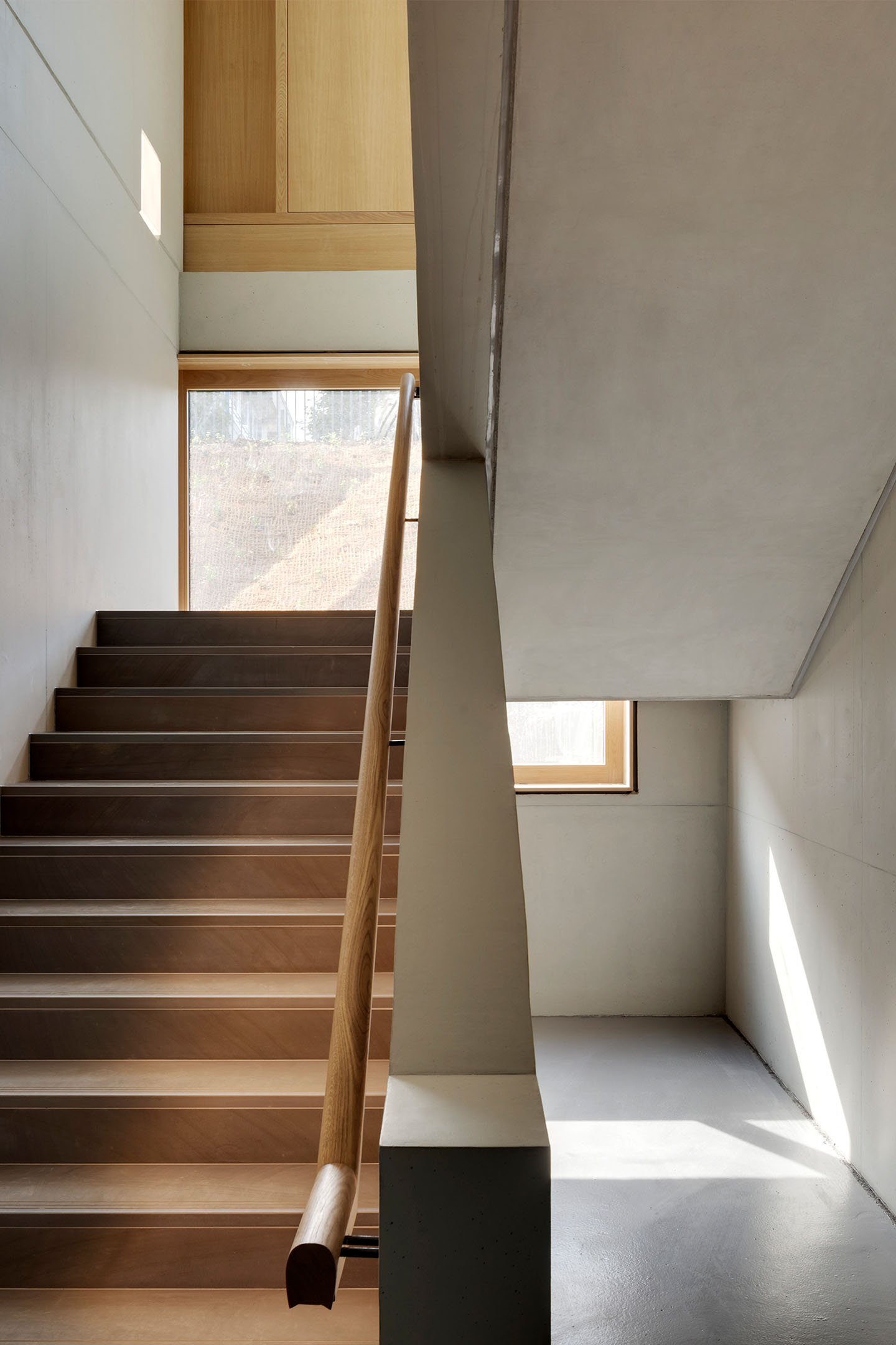 Lichtdurchfluteter Treppenaufgang mit Elementen aus Holz und Beton