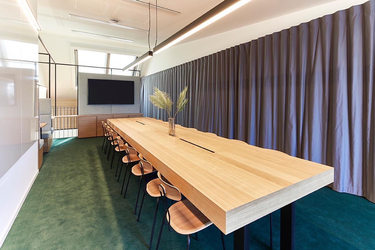 Grosser Meetingraum mit langem Holztisch, Teppich und Gardine bei LinkedIn in München