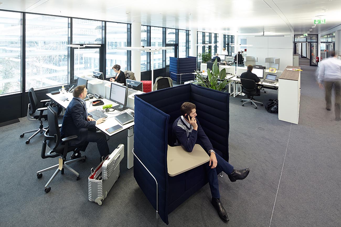 Mit Menschen belebte offene Bürofläche mit vielen Arbeitsflächen bei Vodafone