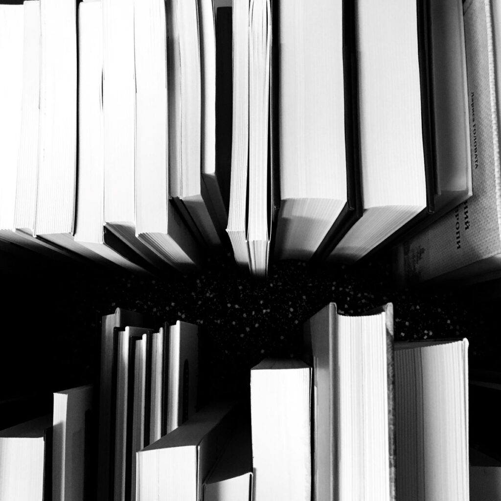 Schwarz-Weiß-Foto von gestapelten Büchern auf einem Tisch