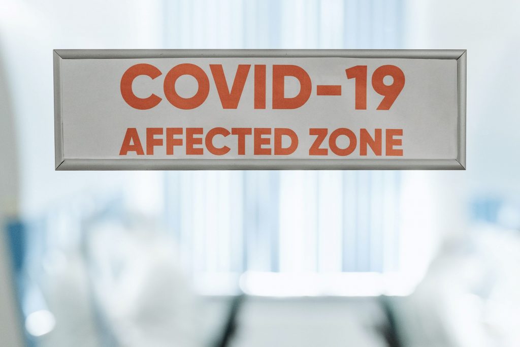 Vor einem Gebäude hängt ein Schild mit dem englischen Hinweis COVID 19 Zone