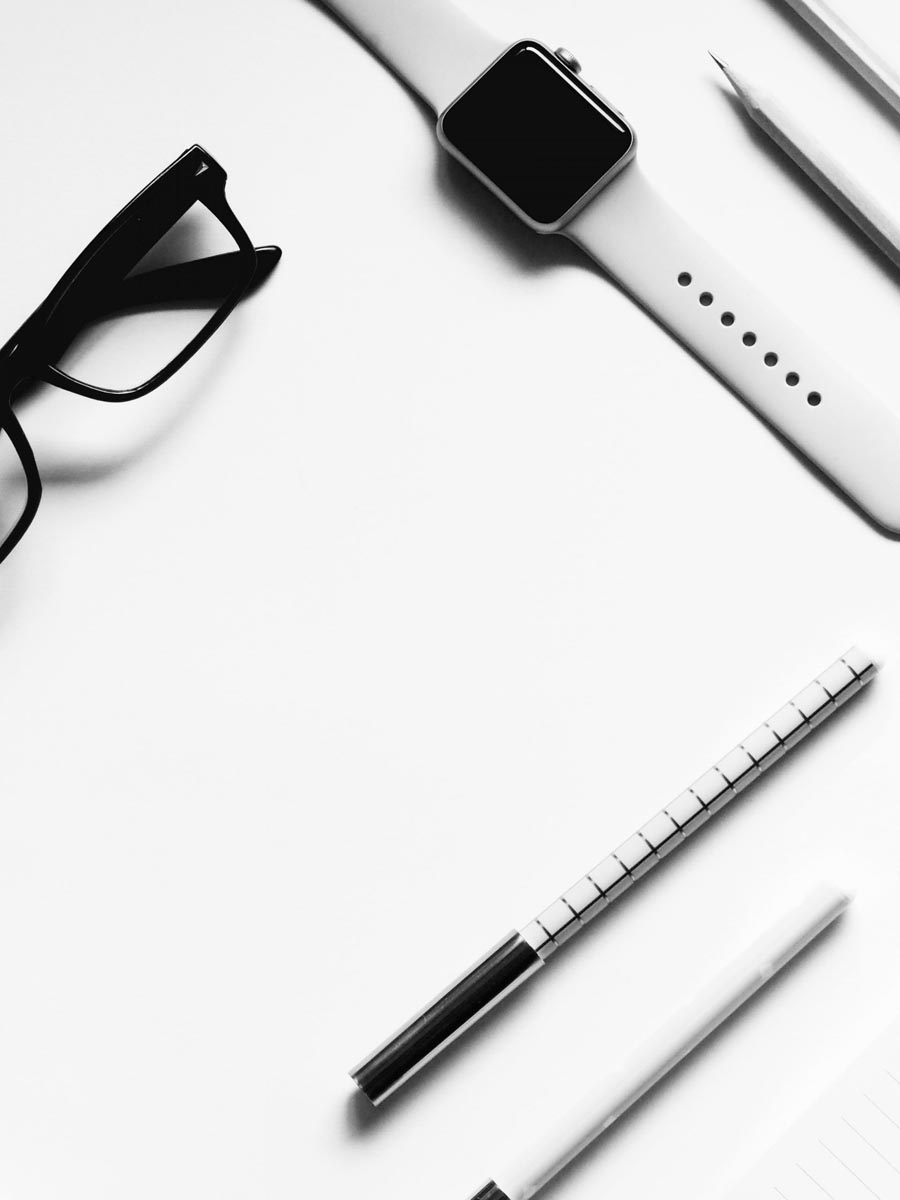 Auf einem weißen Tisch liegen eine weiße Apple Watch weiße Stifte und eine schwarze Brillenfassung