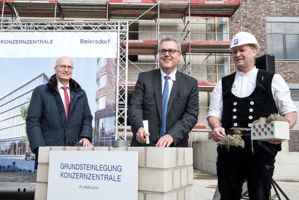 Grundsteinlegung auf der Baustelle im März 2019 des neuen Beiersdorf-Campus mit Hamburgs Oberbürgermeister Peter Tschentscher, dem damaligen Vorstandsvorsitzenden der Beiersdorf AG Stefan De Loecker und einem Bauarbeiter