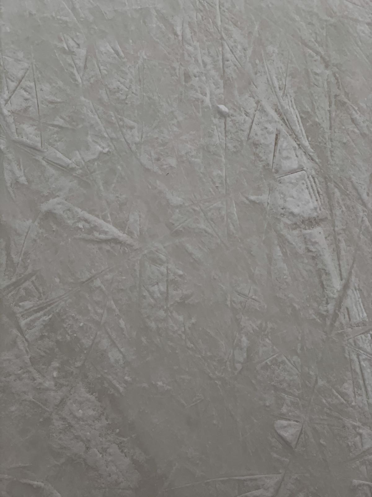 eine wild verputzte weiße Wand mit sichtbaren Spachtelspuren