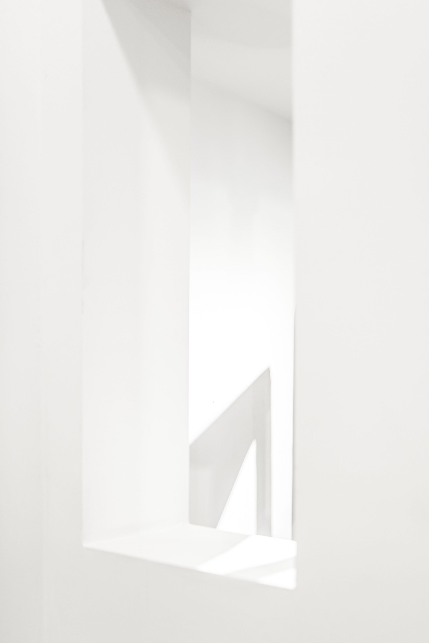 monochromes weißes Bild das einen Fensterausschnitte zeigt und mit Licht und Schatten spielt