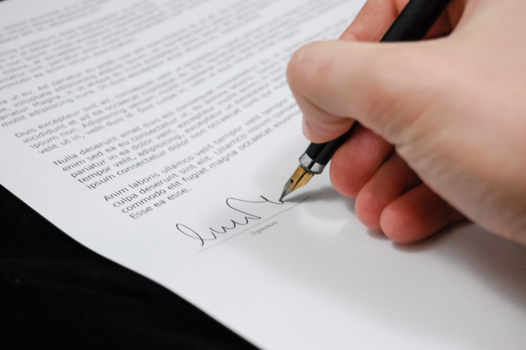 weiße Männerhand signiert ein Dokument mit Füllfederhalter