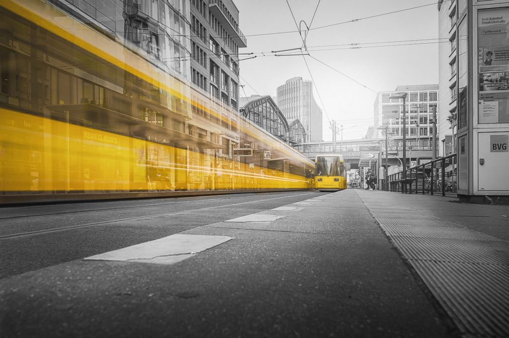 Zwei gelbe Bahnen der BVG in Berlin passieren die Haltestelle Friedrichstraße in einem schwarz-weiß Foto