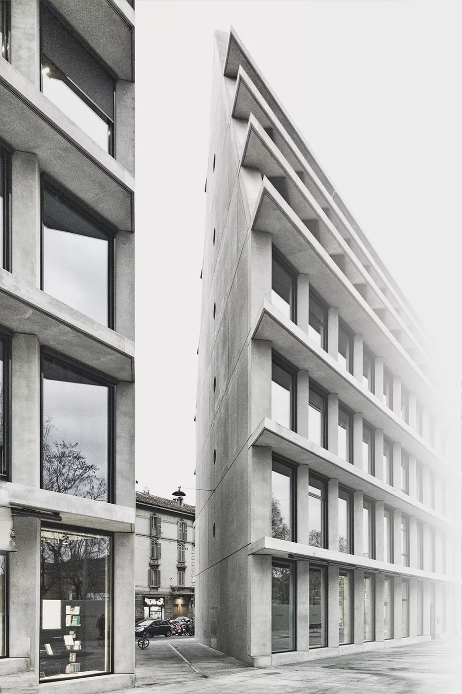 Schwarz-Weiß-Foto von zwei spitz aufeinander zulaufenden Gebäuden, zwischen denen sich eine Lücke bildet