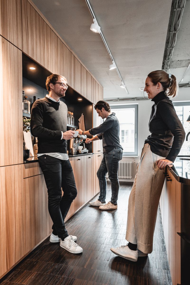 Menschen stehen in einer Holzküche und machen Kaffee.